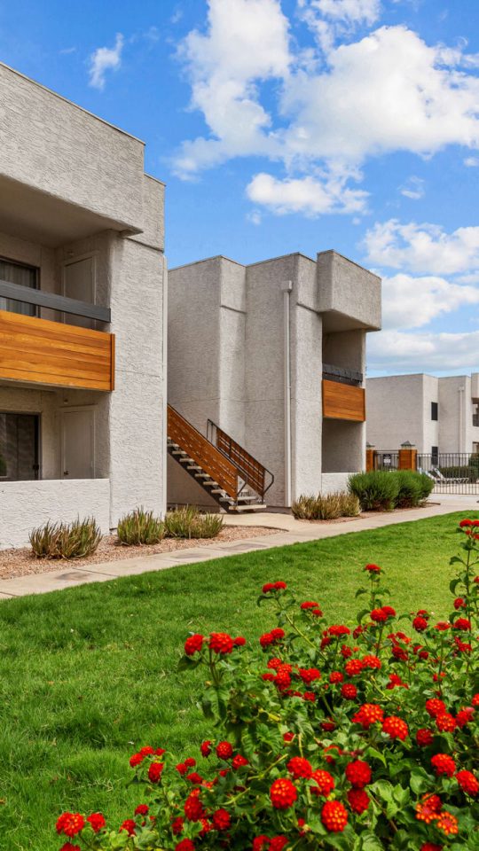 the exterior of an apartment complex with flowers and bushes at The Tides on 27th